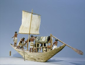 A model of a sailing boat with the pilot in the bow and the owner resting under a canopy