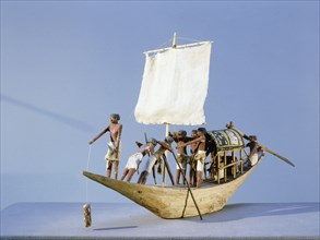 A model of a sailing boat with the pilot in the bow and the owner resting under a canopy