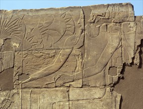 Relief from the walls behind the processional colonnade of Amenophis III depicting Tutankhamun offering flowers to a seated deity