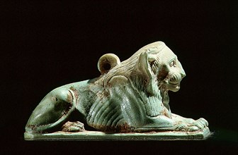 Glazed composition figure of a seated lion, with suspension loop on back