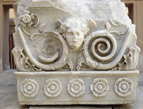 Relief carving depicting a winged head framed by plant tendrils and flowers