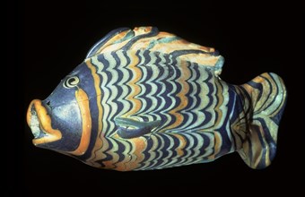 A small painted core glass unguent container in the form of a tilapia fish which was a symbol of rebirth