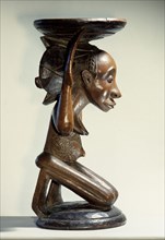 Chiefs stool supported by kneeling woman