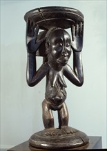 Stool or bowl supported by standing woman