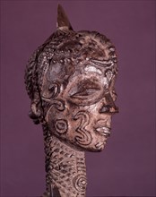 A male figure with elaborate scarification designs on his face and body