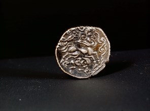 Low alloy coin showing a human headed horse guided by a person waving a torque
