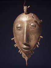 A gold pendant in the form of a stylized head