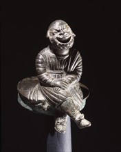 Bronze figure of a comic actor seated on a cylindrical lid, possibly from an incense burner
