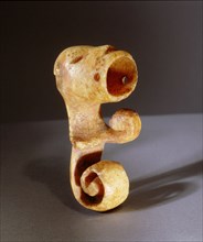 Ivory object, possibly an amulet, carved with a wide mouthed animal face and spiral tail