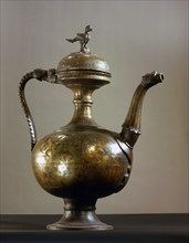 Brass ewer with baluster shaped body, bird finial on lid, handle and spout in the form of a lions head