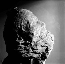 Cast of a mans head with his mouth partly covered with lava