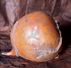 An engraved gourd with depictions of airplanes flying over village huts