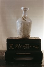 A vase with a white glaze, serrated body and small flower motif painted in black