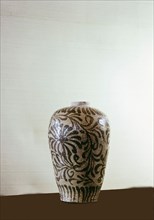A vase decorated with a stylized pattern of leaves and flowers