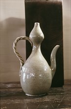 A wine ewer in a double gourd shape with a white glaze, decorated with a large flower, possibly a lotus