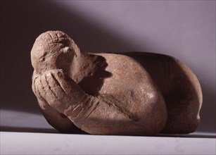 A terracotta figure of a crouching man with his hands covering his face