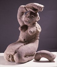 A terracotta figure of a kneeling woman with her hands on her head