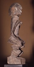 A wood sculpture of a woman, possibly an ancestor figure