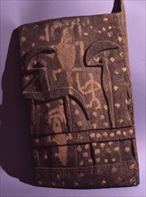 A shutter like door from a Dogon granary sculpted and painted with a horse and rider and other images
