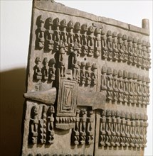 A shutter like door with lock, from a Dogon granary sculpted with rows of figures which may refer to the founding ancestors of the owners family or village