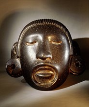 Stone mask of Xipe Totec, the Flayed Lord, dressed in the skin of a sacrificial victim
