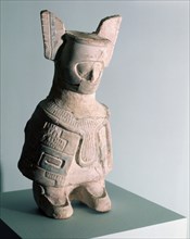 Standing figure wearing a cloak and a winged headdress