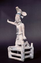 Figurine of a speaker on a rostrum wearing a deer headdress