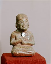 Figure of a woman wearing a pendant made from polished iron ore