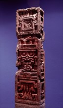 Stone column showing the face of Tlaloc, with protruding teeth and a tongue in the form of a maize plant