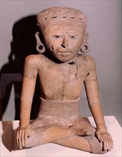 Seated figure of a woman wearing a wrap over skirt and ear spools