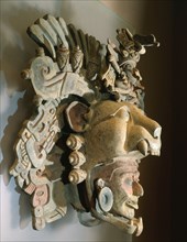 Deity emerging from a jaguarss mouth To the side of the head are cobs of corn, glyphs & stylized serpents