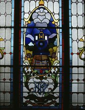 An approaching train with its headlamp alight appears in this detail of a stained glass window in Dunedin Railway Station