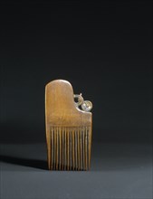 A wooden haircomb, worn in a mans topknot
