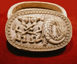A Benin ivory box showing two Portuguese soldiers fighting beside a slaughtered dragon, the latter probably copied from a European print