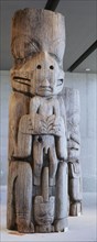 Section of a house frontal pole showing a bear holding a man
