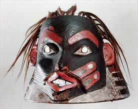 A helmet and mask carved from a single piece of wood and portraying a high born man