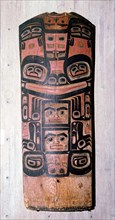 A carved and painted cedar board with a design showing ancestry and social position