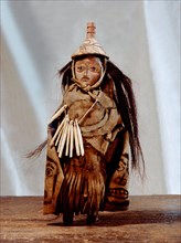 Figire of a shaman, dresses with a breast plate, apron cloak and wearing a hat