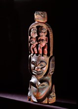 Model totem pole with paired figures below bird crest