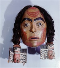 Mask of a girl with red painted facial markings and and braided human hair