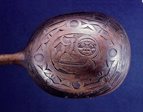 An unpainted shamans rattle carved in low relief