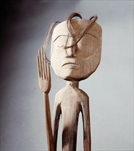 A carved figure representing a shaman with raised hand
