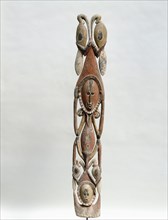 Carving of a squatting female clan spirit figure with two hornbills, surmounting a second head, also with hornbills, from a Maprik region mens society meeting house
