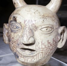 A modelled head of pale clay with red brown geometric patterns