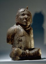 A figure of a seated prisoner with bound hands and a rope around his neck, possibly a sacrificial victim