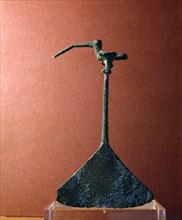 An instrument of beaten metal with a handle in the form of a small, long billed bird