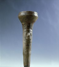 A tubular object decorated with a face and geometric patterns