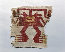 Fragment of a cloth onto which is embroidered a stylized anthropomorphic figure in dyed alpaca wool