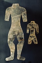 Two silhouettes of mutilated human figures cut from thin sheets of mica