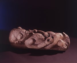 A soapstone nomoli depicting a woman with body scarifications, lying on her back